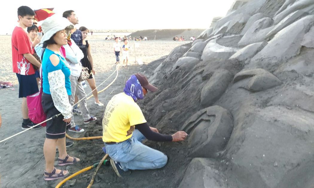 雕塑專家（右1）修復不敵天氣摧殘、表面垮掉的沙雕。圖／高市觀光局提供