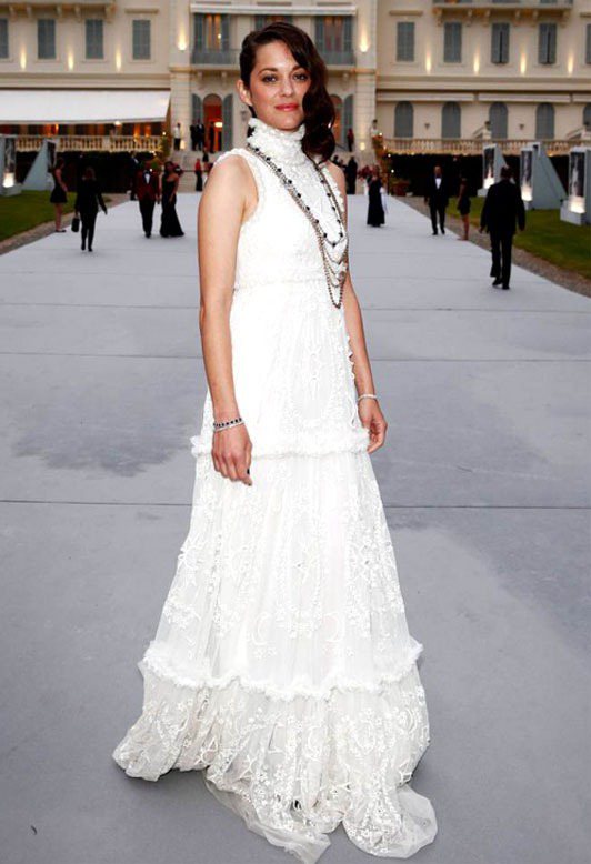 Alexander McQueen 的高領紗質禮服，裙子上的刺繡與立體滾邊設計浪漫優雅，搭配長項鍊讓造型比秀上的模特兒還要完整。圖／擷取自cinemazzi.com