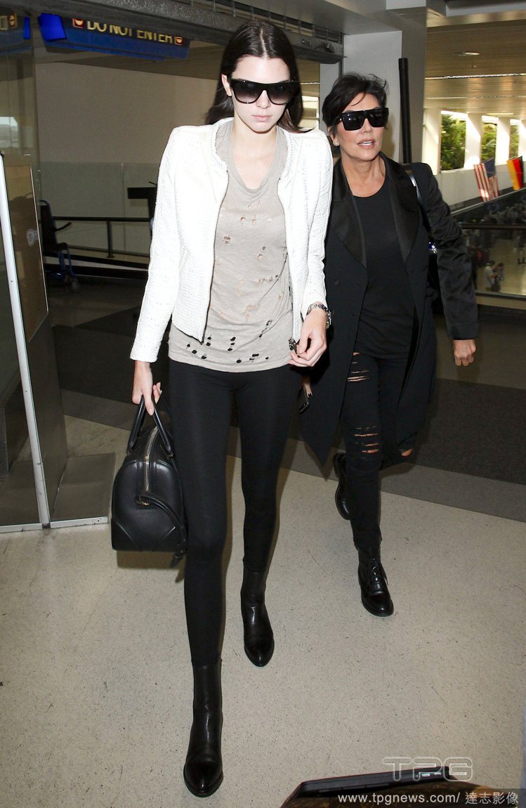 坎達爾珍娜以刷破灰色 T 恤搭配黑色緊身褲，以白色夾克打造俐落層次感，一雙黑色短靴與波士頓包讓下半身看起來更有份量。漸層墨鏡則呼應黑色穿搭。圖／達志影像