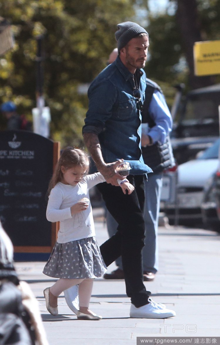 貝克漢趁著天氣好帶著小哈潑上街，這位奶爸不僅牢牢牽著女兒，兩人還拿著點心漫步在太陽下。圖／達志影像
