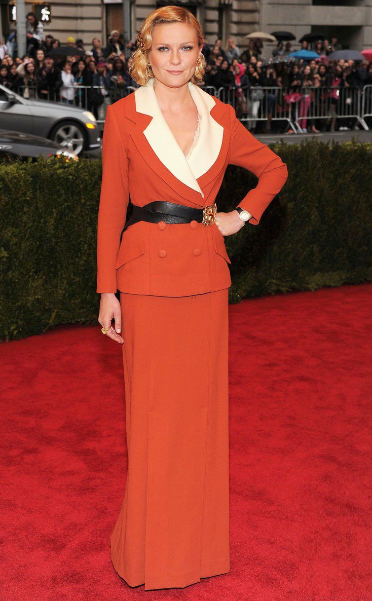 頂著復古髮型的克絲汀鄧斯特選穿橘色Rodarte套裝禮服，既有女強人的感覺又帶有「深V的性感」。圖／達志影像