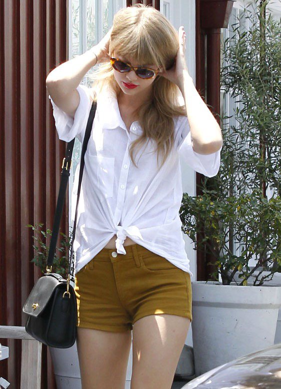 泰勒絲選了一件土黃色的短褲，塗上紅唇的她將襯衫隨意綁個結露出肚子，帶點度假風的悠閒與性感。圖／達志影像