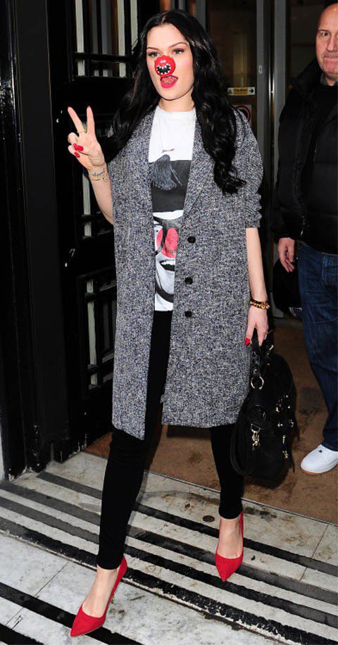 Jessie J穿著可愛的小丑T恤搭配灰色毛呢大衣，紅色尖頭高跟鞋與小丑的鼻子配色相呼應，女人味之中透著頑皮氣息。圖／達志影像