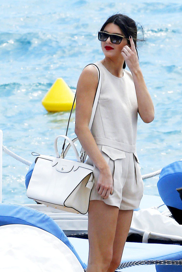 新一代 It Girl Kendall Jenner 肩揹Longchamp Le Pliage Héritage 20周年紀念包款搭配一身純白套裝演繹俐落清爽風格。圖／LONGCHAMP提供