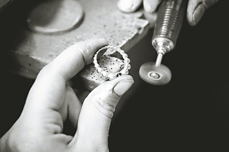 打磨工匠逐一為指環上每顆圓珠，按大小漸變的比例仔細拋光。圖／梵克雅寶提供