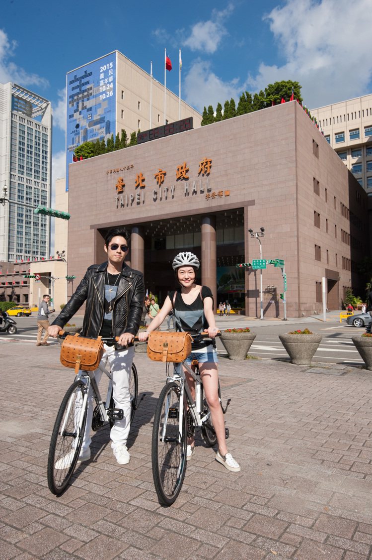 「MCM遇見台北 - M Bike活動」，小S與吳建豪騎上M Bike於台北市政府前合影留念。圖／MCM提供
