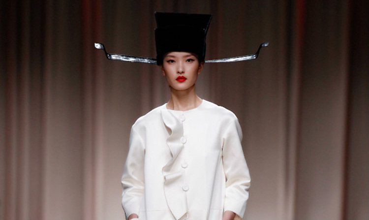 Moschino 2014 早春上海秀中，超模杜鵑頭戴烏紗帽出場，雖然和身上的白色洋裝不太搭，但驚喜感十足。圖／擷取自blouinartinfo