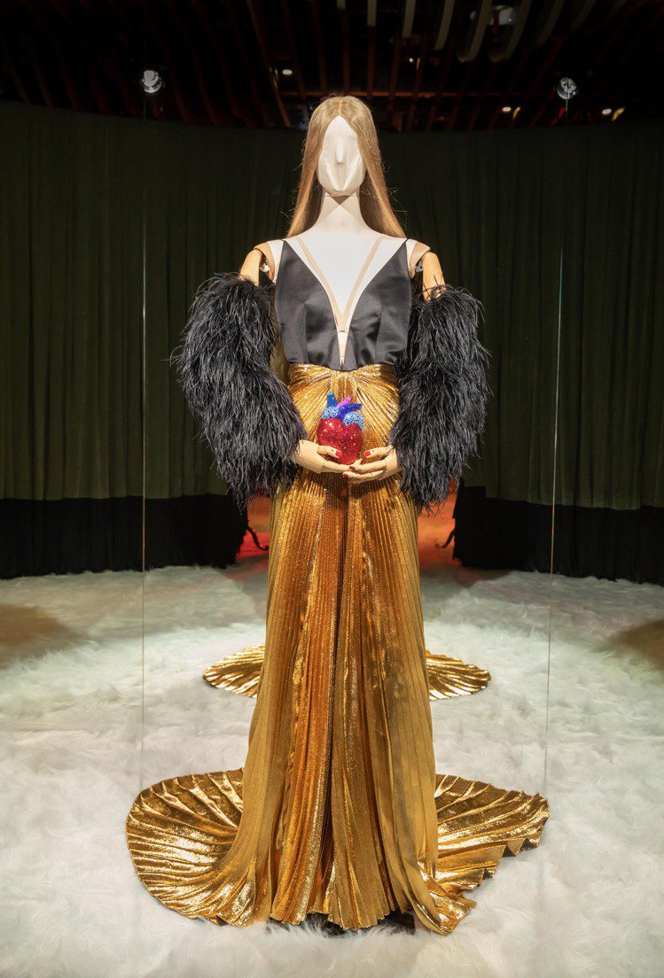 瑪麗蓮夢露在《紳士愛美人》中的造型啟發的金色百摺裙羽毛裝飾禮服，心臟造型的鑽飾晚宴包，彰顯Alessandro Michele的浪漫與奇想。圖／GUCCI提供