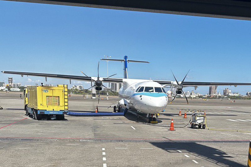 華信AE335從高雄小港機場起飛後，疑因發動機故障（擺放三角錐位置上方）回降小港機場。圖／旅客提供