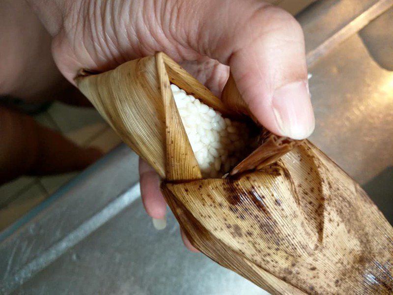 一名網友到市場購買了一串鹼粽，但沒想到回到家後打開粽葉一看裡面包的竟是「生米粒」。圖擷自爆怨公社