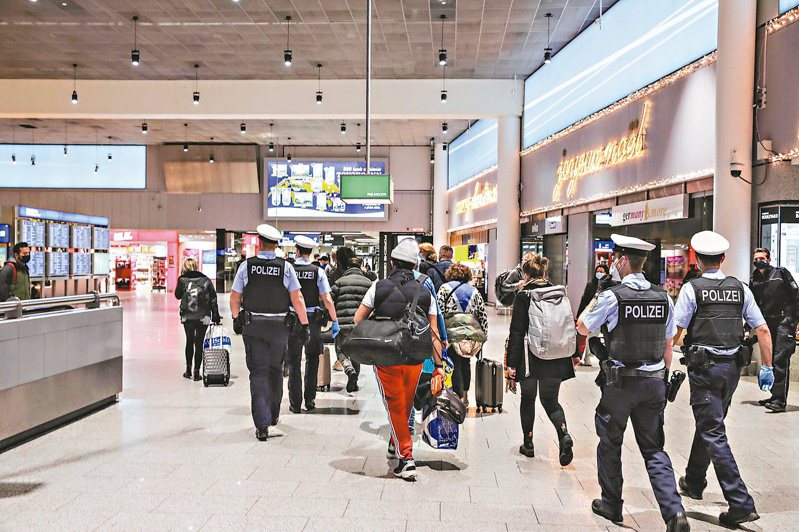德國法蘭克福機場駐警廿一日將一群旅客從病毒檢測中心送往登機門。德國已採取暫停英國班機和乘客入境措施，防堵變種新冠病毒。（法新社）