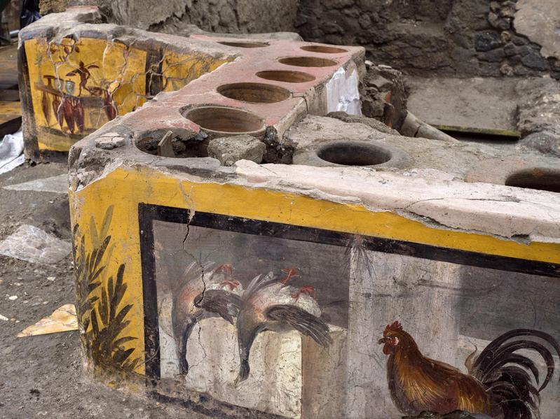 考古團隊最近在義大利龐貝發現一處保存異常完整、有鮮艷壁畫裝飾的熟食攤，地處當年繁忙的銀婚禮街與陽台巷交叉路口，櫃台上有一個個圓孔作為放置食物陶罐之處，可說是羅馬時代的「小吃攤」。 歐新社