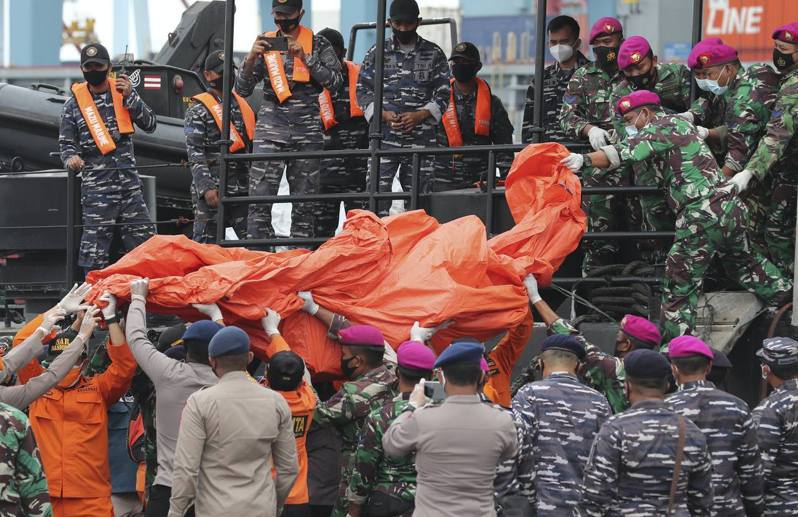 1月10日，在印尼雅加达的丹戎不碌港，士兵和警察用帆布帐篷搬运在爪哇岛附近海域发现的残骸。（AP）(photo:UDN)
