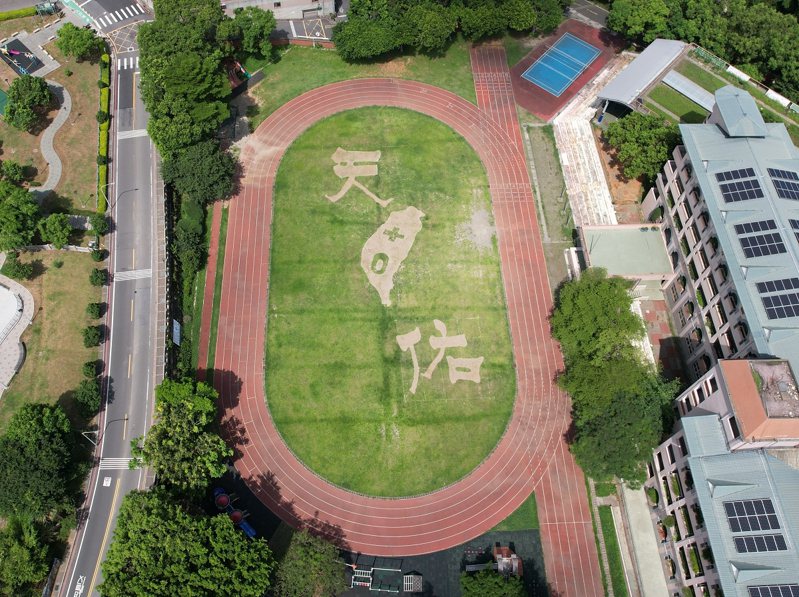 淡水區新興國小操場草皮，大型「天佑」兩個字，加上台灣的圖樣裡頭寫著「+0」，這是學校工友林敏智的創意。 圖／紅樹林有線電視提供