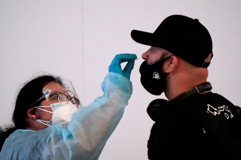 工作人员22日在美国洛杉矶国际机场，为旅客筛检新冠病毒。  路透(photo:UDN)