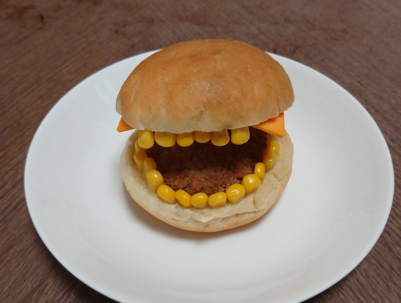 一位日本網友用玉米裝飾漢堡，卻反而讓漢堡變得像會吃人的怪獸一樣。圖擷取自twitter