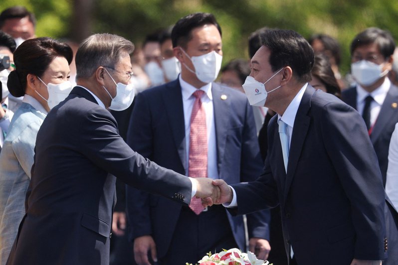 南韩新总统尹钖悦（右）与前总统文在寅在10日的总统就职典礼握手致意。路透(photo:UDN)