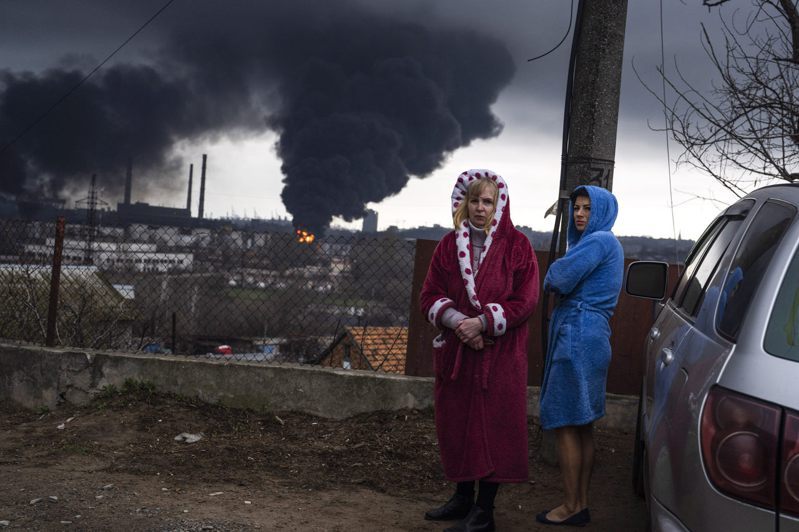 图为黑海港市敖德萨（Odesa），着长袍的妇女与身旁遭到俄罗斯炸弹攻击升起的黑色烟雾。美联社(photo:UDN)