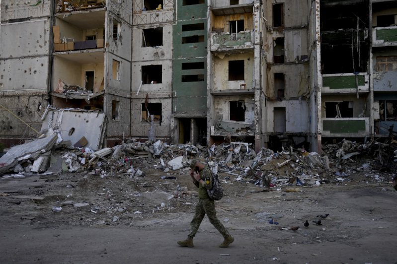 一名乌克兰军人经过北部切尔尼戈夫一栋被摧毁的大楼。美联社(photo:UDN)