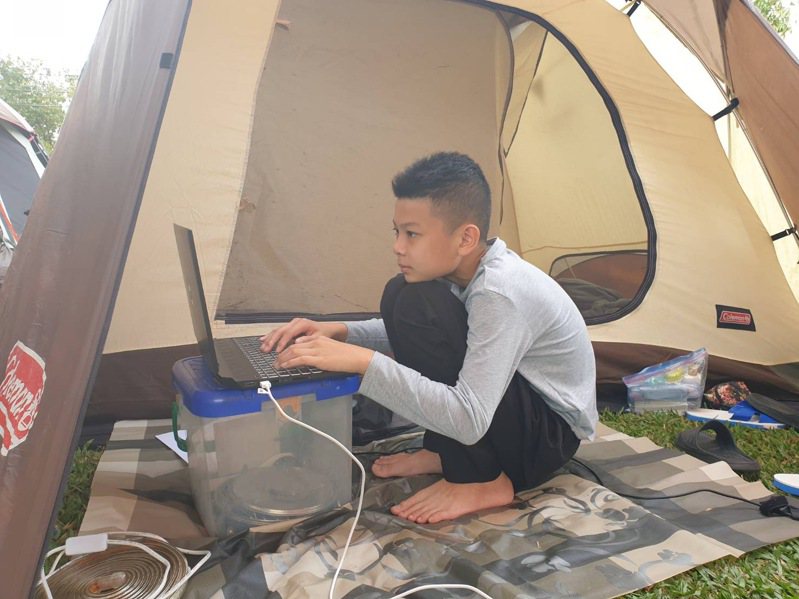 國中1年級學生蔡澄岳在露營帳篷內，以「在爬山路上」為題參加聯合盃作文比賽。圖／家長提供