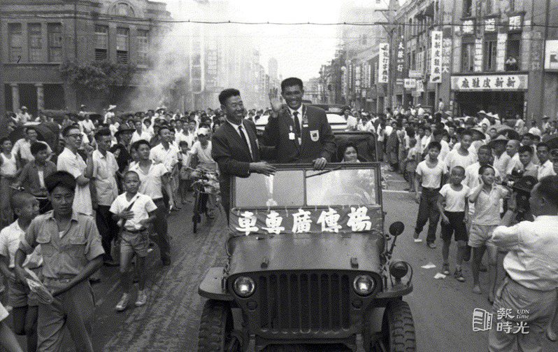 榮獲第十七屆世運十項運動亞軍的中華民國選手楊傳廣，十五日上午搭機返國，楊傳廣(右)及他的家人，和一同在美國受訓的魏振武(左)教授，乘車遊行市區，接受民眾熱烈的歡迎。 圖／聯合報系資料照（1960/09/15　陳維在攝影） 