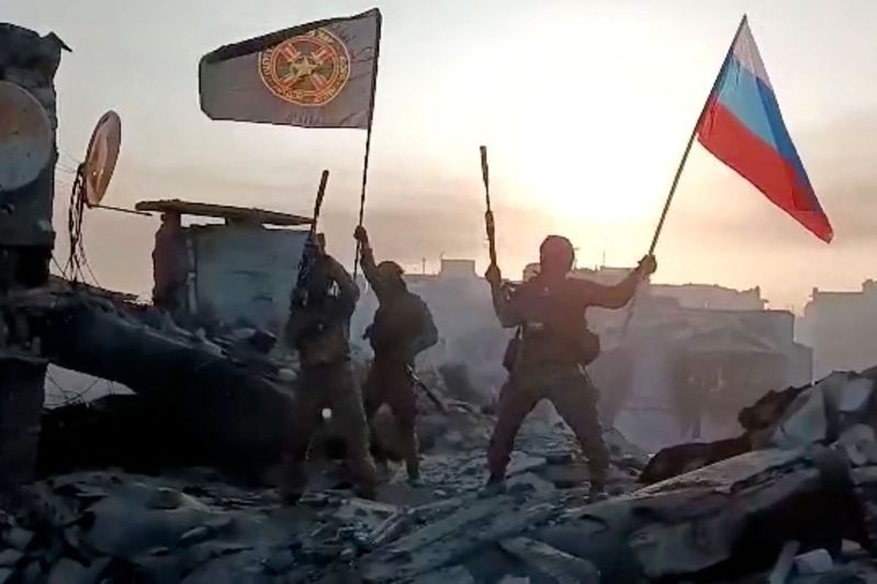 俄方宣稱已完全攻占烏東要地巴赫姆特。圖為瓦格納傭兵20日在巴赫姆特揮舞俄國國旗及瓦格納旗幟。（法新社）