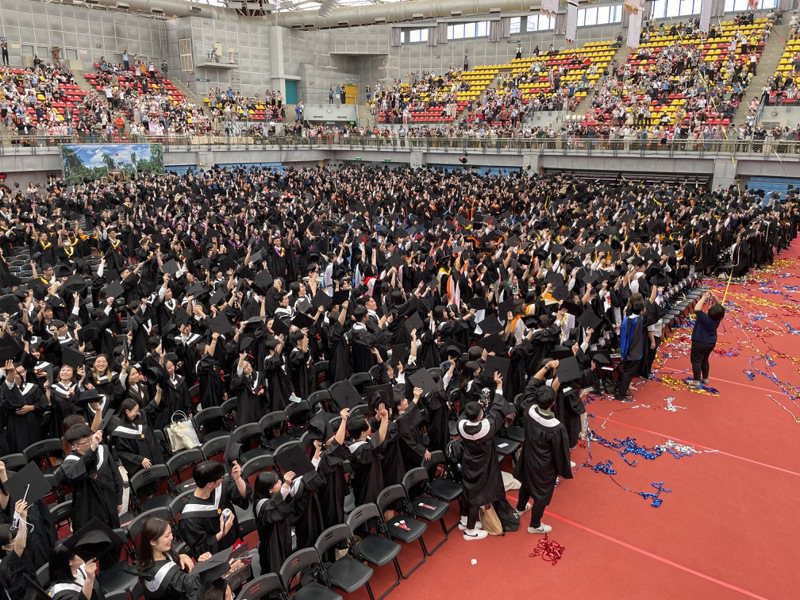 國立台灣大學今天舉行畢業典禮，學生禮成時揮舞學士帽，向家長致意。記者許維寧／攝影