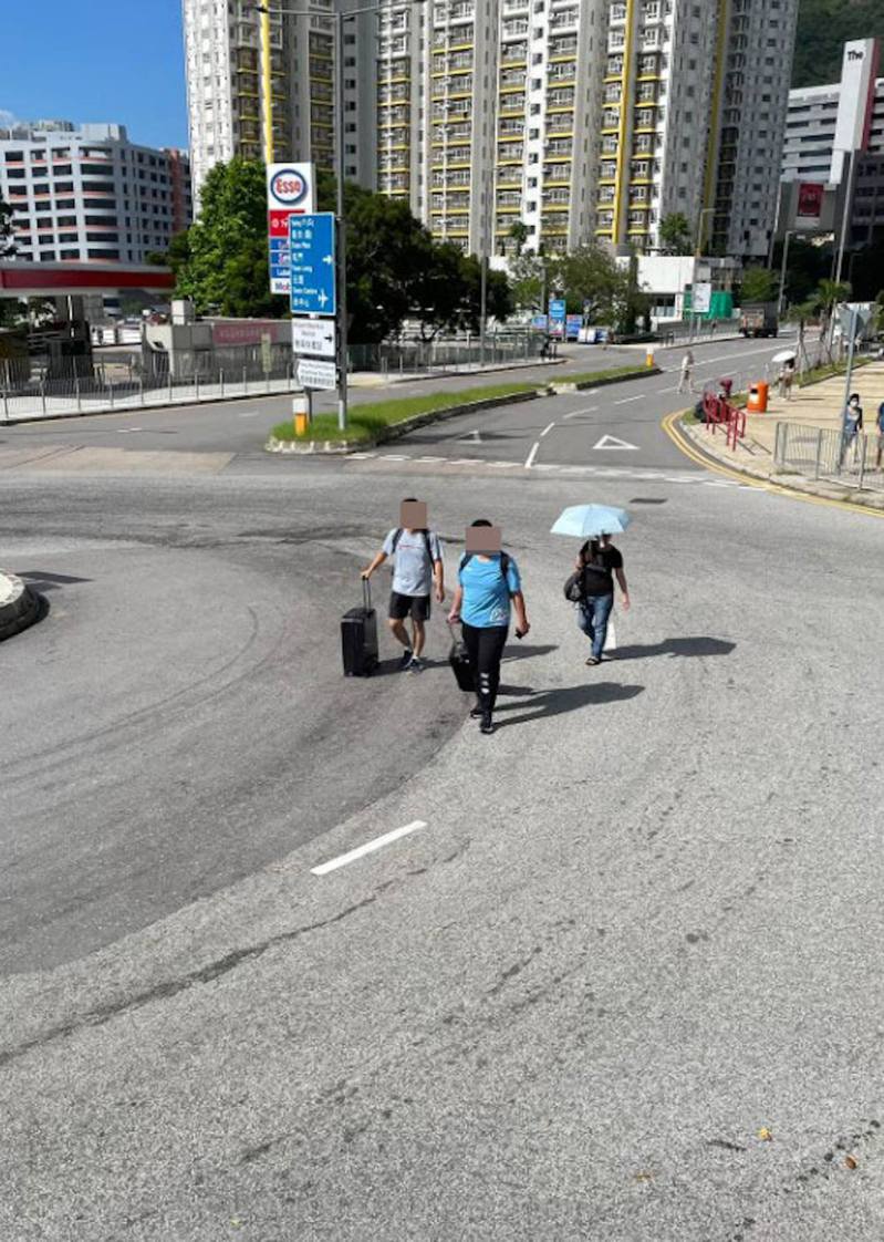網上流傳照片顯示有數名拖着行李箱，相信是旅客的人士竟然大搖大擺行走出青衣路某迴旋處，在馬路上「打橫行」。（FB「青衣街坊吹水會」圖片）