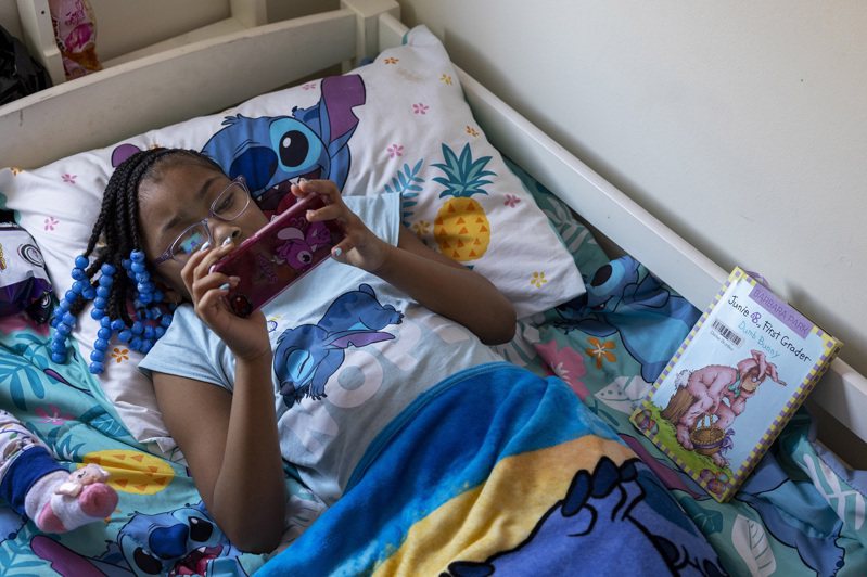 一名美國兒童躺在床上玩手機遊戲，資料照片。美聯社