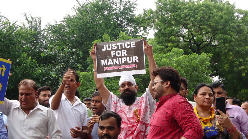 印度小老百姓黨（AAP）25日在新德里發動示威，聲援曼尼普爾省（Manipur）在種族暴亂期間受害的婦女。圖為一名男性示威者身穿「血衣」，高舉「給曼尼普爾正義」字牌。中央社