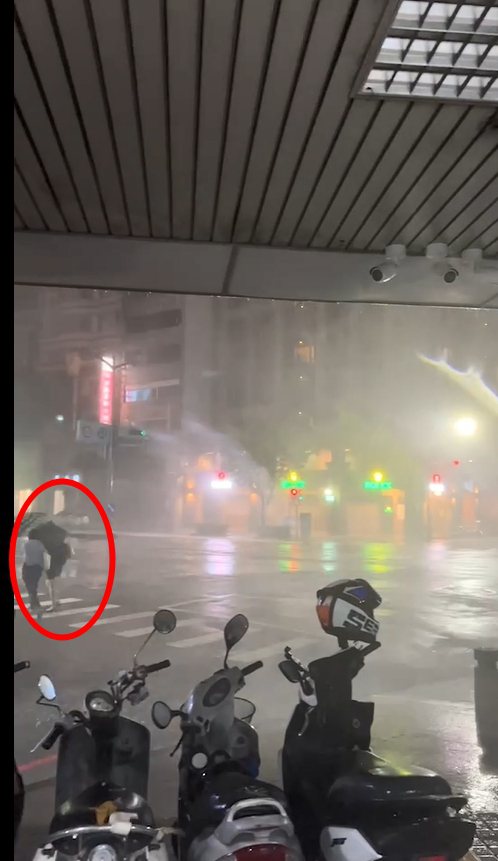 高雄今晚6點後壟罩在中颱海葵暴風圈，颳起強風豪雨，2名年輕女子在五福路和自強三路路口，冒險撐傘過馬路，因雨傘開花嚇到尖叫。圖／取自記者爆料網