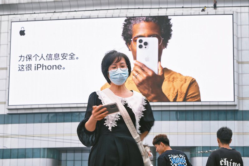 一名女子五月走過北京街頭的蘋果iPhone廣告。（美聯社）