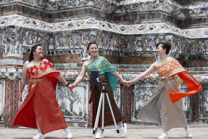 圖為中國大陸遊客穿著租來的泰國傳統服裝，在曼谷鄭王廟拍照留念。(歐新社)