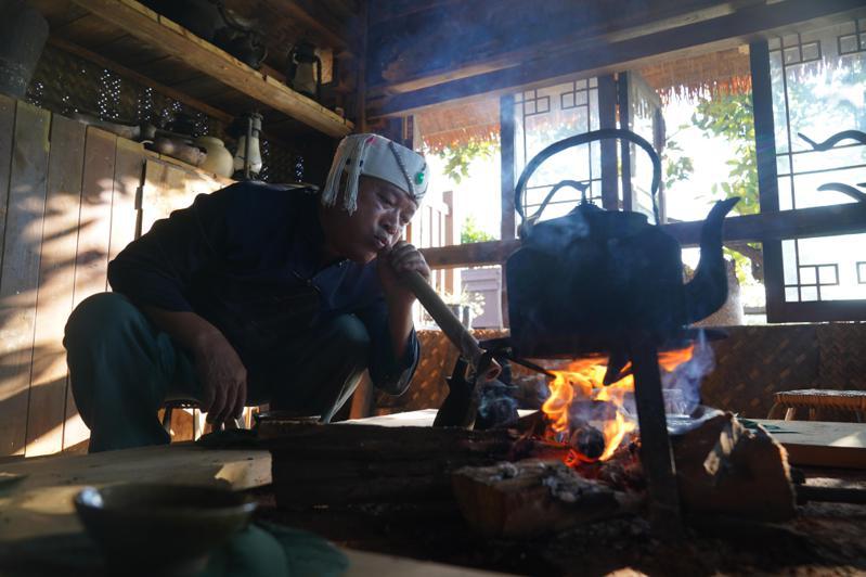 雲南「普洱景邁山古茶林文化景觀」項目成功審請列入《世界遺產名錄》。圖為景邁山傳統手工製茶技藝市級傳承人南康坐在火塘邊，展示布朗族烤茶的製作過程。 （中新社）