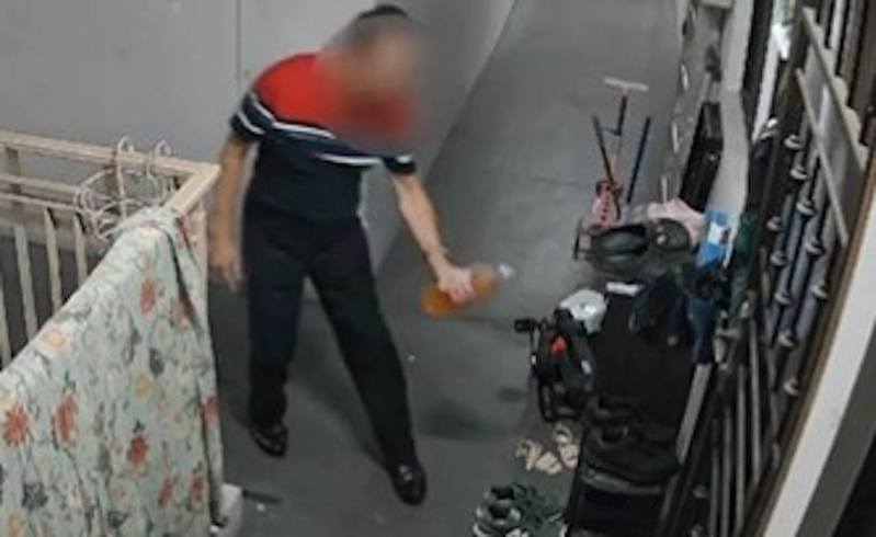 馬來西亞有男子被監視器拍到多次將疑似尿液倒至鄰居家門。（Twitter影片截圖）