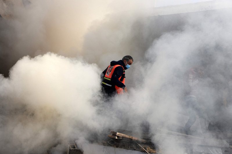 以色列7日轟炸加薩走廊南部的甘尤尼斯後，一名巴勒斯坦消防員站在濃煙之中。法新社