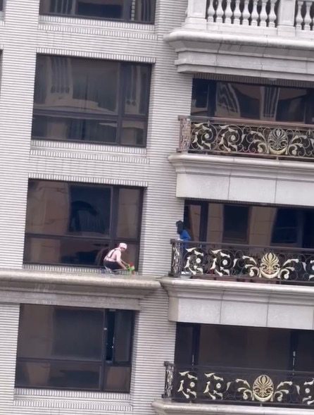 桃園市桃園區藝文二街一棟豪宅，有一名女性清潔人員直接站在20樓窗外平台清理殘留蜂蛹，且毫無安全防護措施，讓民眾看了膽戰心驚。圖／民眾提供
