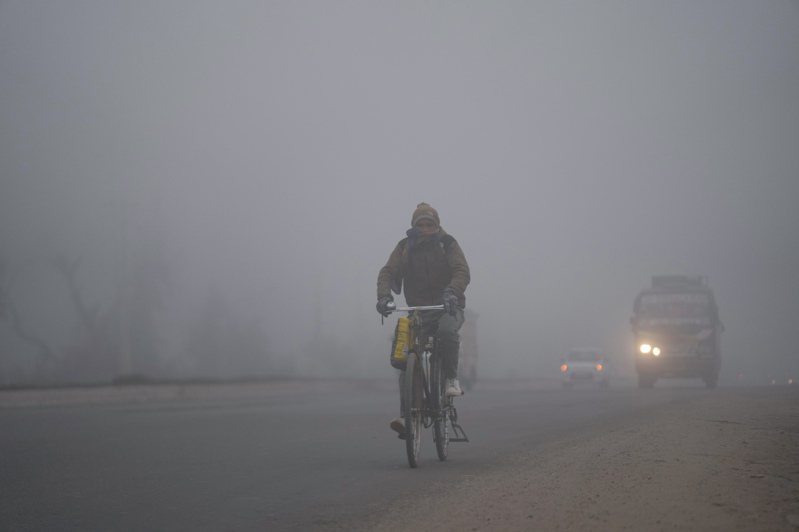 由於濃霧和寒冷籠罩印度北部大片地區，印度首都新德里的航班和火車服務今天連續第二天受到嚴重影響。圖為1月15日，印度查謨一名騎自行車的人穿過濃霧。美聯社