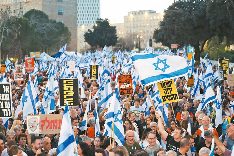 以色列民众三月卅一日在耶路撒冷国会大楼外挥舞国旗抗议，要求政府救回被哈玛斯胁持的人质及总理内唐亚胡下台。（欧新社）(photo:UDN)