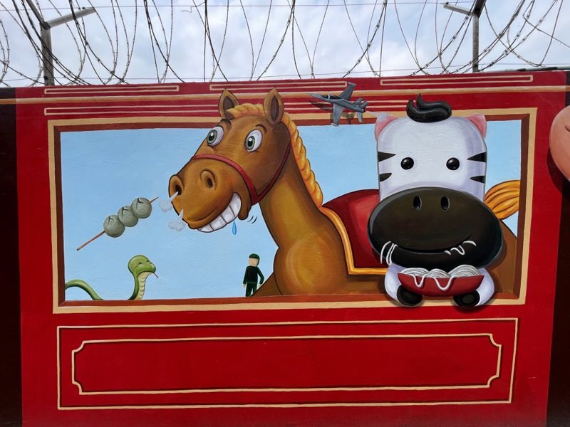 新竹市空軍基地旁靠成功路圍牆最近完成一大片彩繪，畫上以12生肖動物搭鐵路小火車的童趣模樣、還有米粉跟貢丸。記者張裕珍／攝影