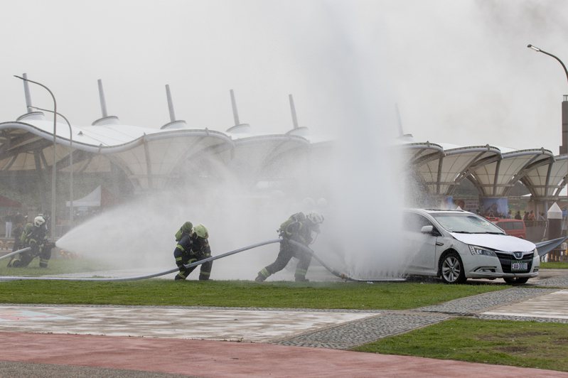 圖為情境模擬電動車起火後，消防隊用特殊器材從車子底盤噴水滅火。記者季相儒／攝影