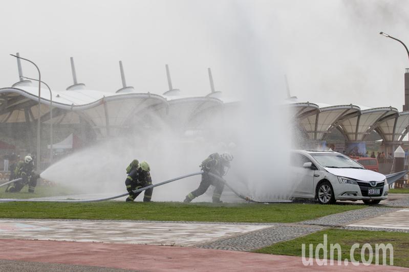 情境模拟电动车起火后，消防队用特殊器材从车子底盘喷水灭火。记者季相儒／摄影