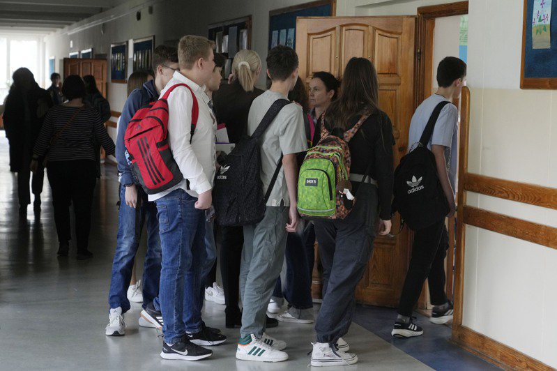 波蘭首都華沙學校的學生魚貫進入教室，開心以後不必寫回家作業 。（圖／美聯社）