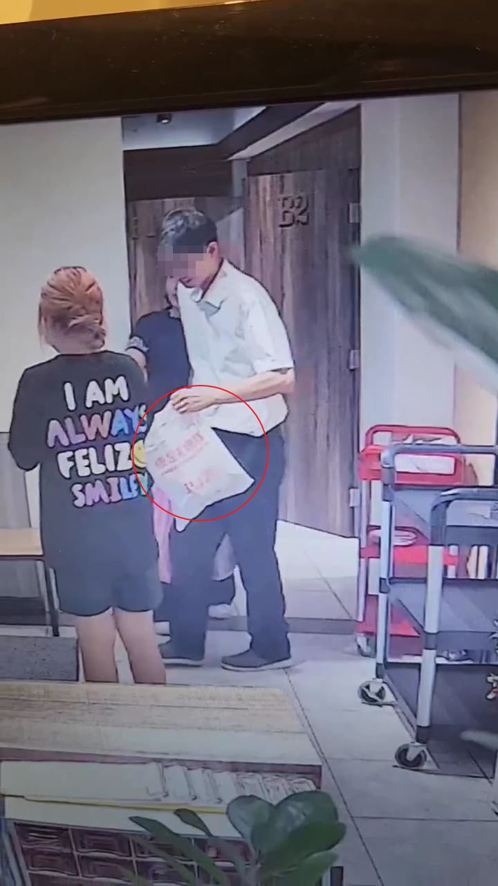 警政署王姓警官离开餐厅时拿著戴玮珊装有衣物及资料的塑胶袋。记者黄子腾／翻摄