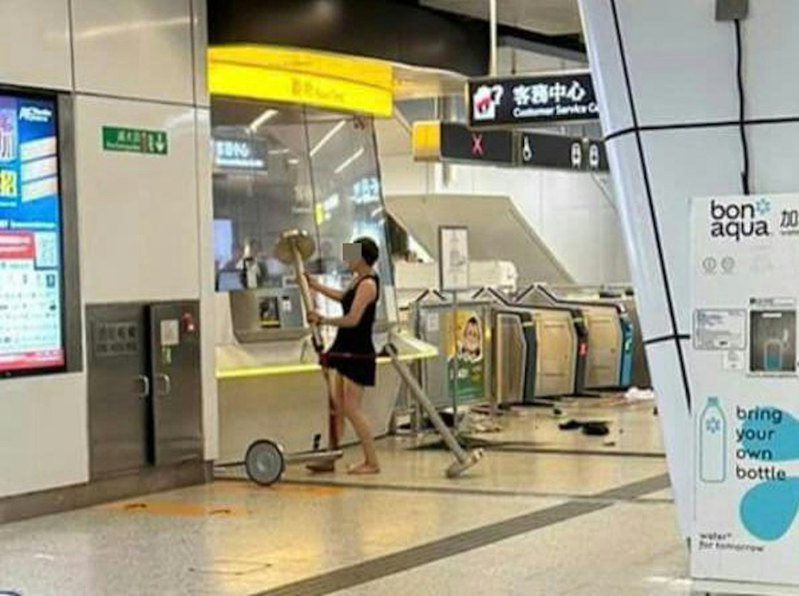 本港網絡瘋傳1組照片，見到觀塘港鐵站內有1名短裙女持排隊欄杆不斷攻擊票務站。（圖片來源：網友「車干」）