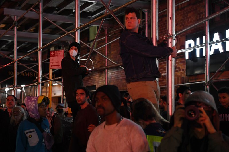 4月30日，紐約哥倫比亞大學附近，人們圍觀警察與抗議者對峙。（新華社）