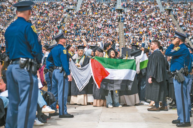 美國安娜堡密西根大學四日舉辦畢業典禮，幾名畢業生在現場拿出巴勒斯坦旗幟，高呼支持巴人口號。（美聯社）