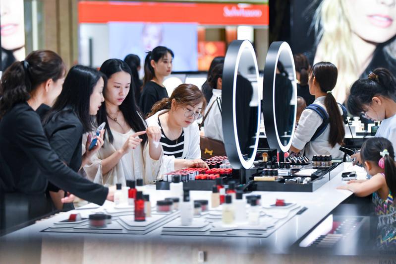 大陸4月財新服務業PMI微降至52.5，圖為海南海口國際免稅城內消費者正在選購化妝品。（中新社）