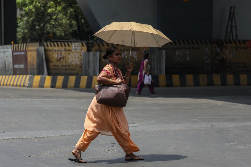 圖為印度一名在艷陽下撐傘的行人。示意圖／歐新社資料照