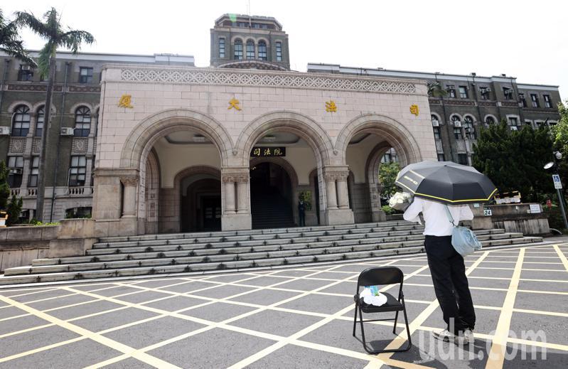 基隆地院法官李岳捧著一束白花、撑著黑伞在司法院前广场「伫立」，据了解，他将站上1天。记者杜建重／摄影